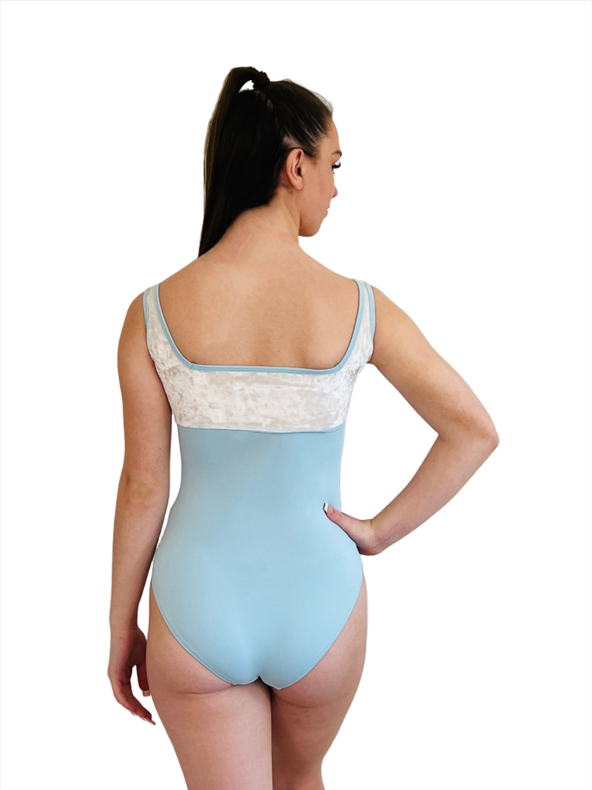 White and blue velour leotard. White velour from bust to straps. Pale blue lycra body. Square neck and blue lycra binding at neck and straps sold by The Collective Dancewear.