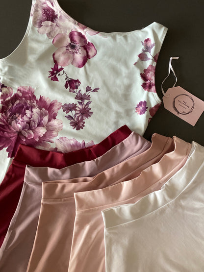 Leotard in pale blue with burgundy flower pattern from The Collective Dancewear with matching skirts in burgundy, lilac, dusky pink, pale pink and white 